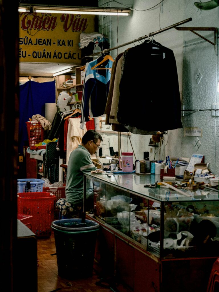 A vibrant portrayal of a tailor shop in Vietnam with a seamstress working diligently among colorful garments.